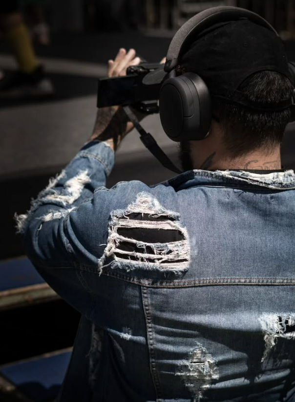 Cinegrafista de costas filmando na rua com fones de ouvido